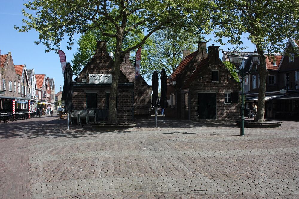 Oude bakstenen panden met puntgevels aan het Spuiplein in Spakenburg, met bomen en een geplaveid plein ervoor