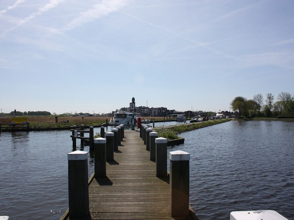 Houten pier met palen die vanaf de haven van Spakenburg het open water van het Eemmeer in loopt
